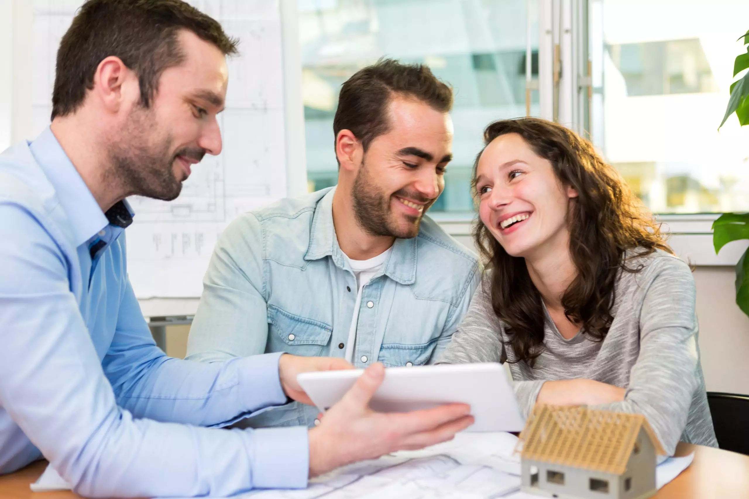 Happy young couple signing a contract with a real estate agent